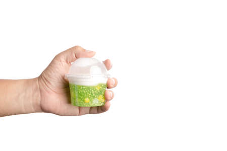 Hand holding plastic cup of sago in coconut milk with corn, Thai traditional dessert on white backgroundの写真素材