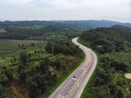 Asphalt road with red coloured surface for help tires tension through mountain and forest in Asian countryのeditorial素材