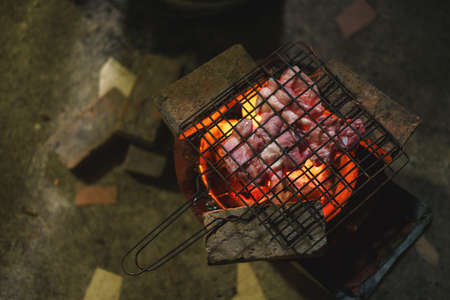 Pork barbecue over burned red hot charcoal on traditional Asian stove