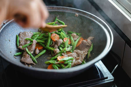 Cooking stir fried string bean vegetables with pork and carrotsの写真素材