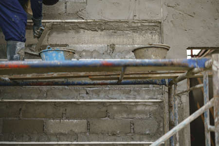 Worker labor building wall and UPVC groove line with plaster cement at house construction site