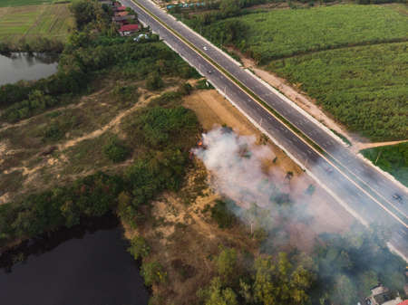 Burning junk with smoke pollution next to high way road at rural Asian countrysideの写真素材