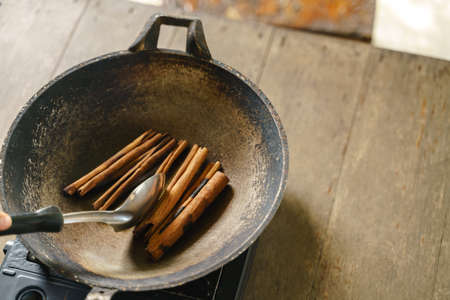 Frying cinnamon stick with pan over portable stove for enchant smell fragmentの写真素材
