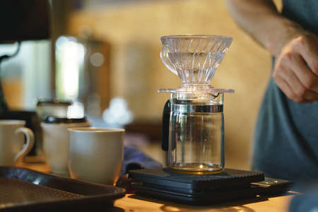 Coffee drip process by pouring hot water from kettle though ground berries bean with filterの写真素材