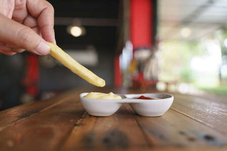 Eating french fries with mayonnaise and tomato sauce dipの写真素材