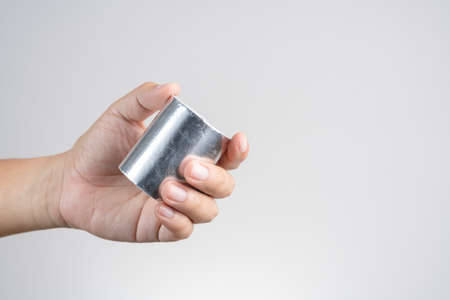 Hand holding adhesive aluminum foil tape for padding on white backgroundの写真素材