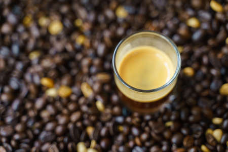 Small shot cup of espresso coffee with roasted bean as background