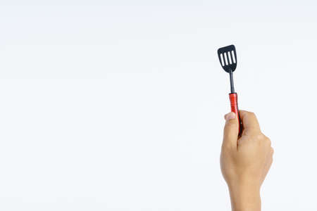 Hand holding small kitchen turner toy on white backgroundの写真素材