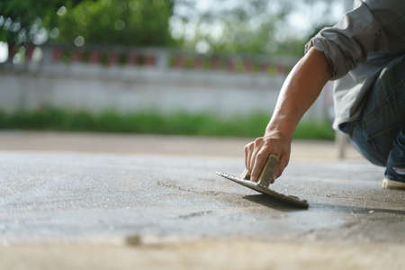 Asian worker labor working and scrubbing with concrete cement floor at house construction siteの写真素材