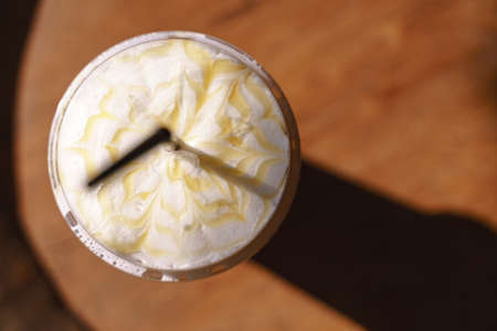 Plastic cup of iced latte coffee with milk froth and sweet syrup in cafeの写真素材