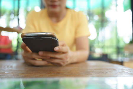 Woman using a smartphone while waiting for foodの写真素材