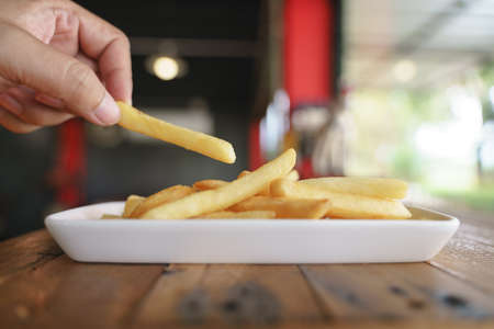 Hand picking up french fries for eatの写真素材
