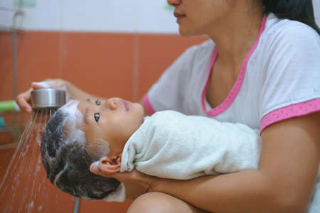 Asian boy about 2 years and 3 months old being washed and showered by his motherの写真素材