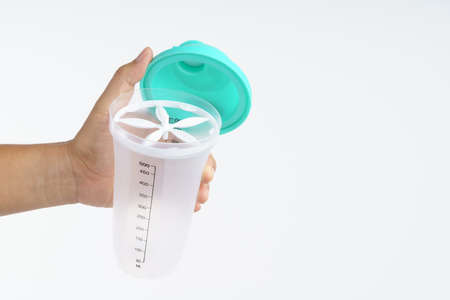 Hand holding plastic water bottle with powder shaker for making drink on white backgroundの写真素材