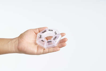 Hand holding medicine pills plastic box container on white backgroundの写真素材