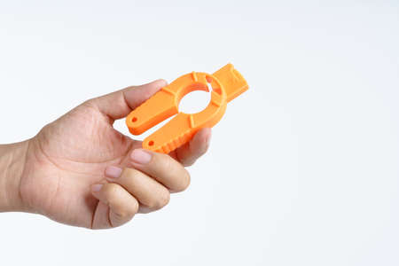 Hand holding plastic bottle cap opener with tin can ring pull at the tip on white background