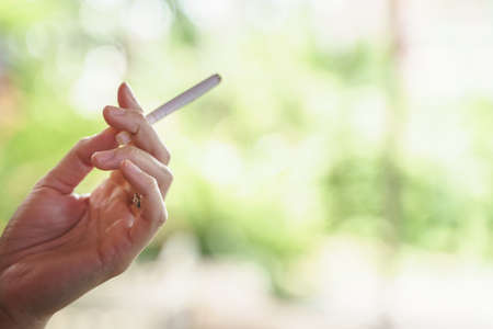 Woman hand holding burning and smoking cigarette