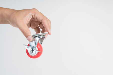 Hand holding metal caster wheels with soft plastic tyre for furniture on white backgroundの写真素材