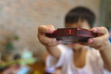 Kid hand holding restaurant queue wireless pager for calling the customer