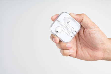Hand holding box of mobile phone earphones on white background