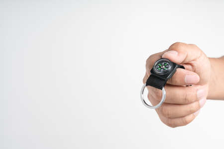 Hand holding metal hook with magnetic compass on white background