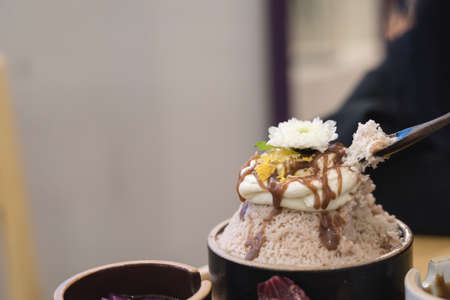 Bingsu or Asian Ice flake dessert with sweet milk cream whip syrup and flower decoration