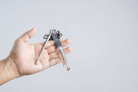 Hand holding kitchen classic can opener on white backgroundの写真素材
