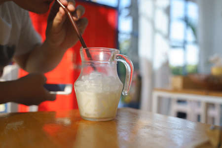 A man addicted to mobile phone while drinking milk from jug in the cafeの写真素材
