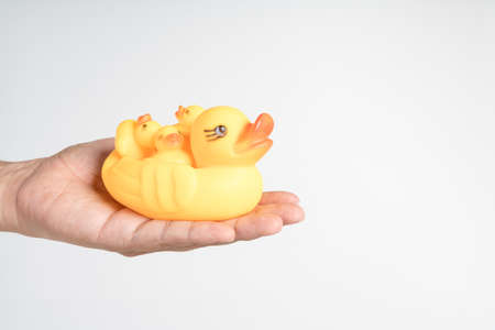 Hand holding yellow rubber duck boat for pool or kid bath on white background