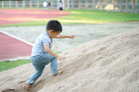 Asian boy about 3 year and 8 months playing with pile of sand and toy at public parkの写真素材