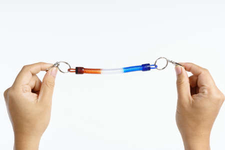 Hand holding retractable rubber spring coil key chain on white backgroundの写真素材