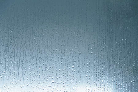 Water drop and droplet flowing down on shower glassの写真素材