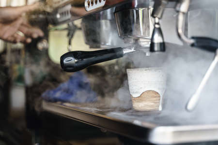 Hot water steaming from coffee blending machine with making milk frother in the backgroundの写真素材