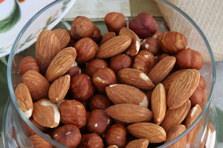 Almonds and hazelnuts in a glass containerの写真素材