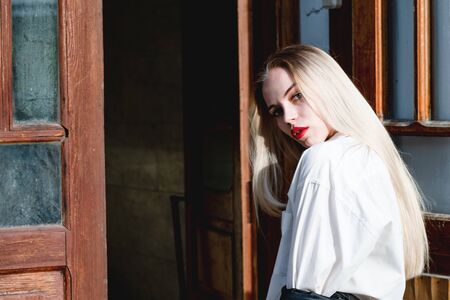A beautiful, young girl in a white shirt opens the door.