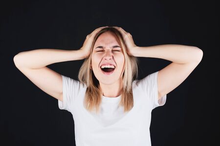 Emotional portrait of a girl holding her head in her hands, feeling pain.の写真素材