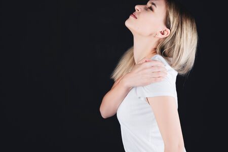 Portrait of a girl who holds on the shoulder with hands experiencing pain.の写真素材