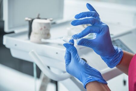 Female dentist doctor holds dental mouthguard in hands, splint therapy in dentistry to correct bite.の写真素材