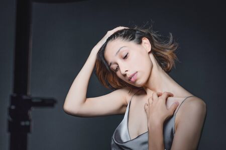 Portrait of a beautiful, sensual girl on a gray background in a gray dress. Youth and skin care conceptの写真素材