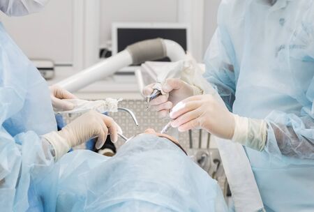 Close-up of the hands of a dentist and nurse surgeon over an operating room during a dental implant operationの写真素材