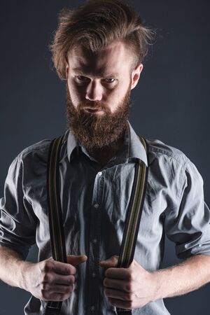 Young, handsome man with a beard posing on a black background in the studio.