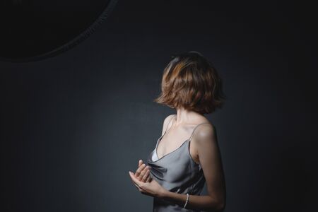Portrait of a beautiful, sensual girl on a gray background in a gray dress. Youth and skin care conceptの写真素材