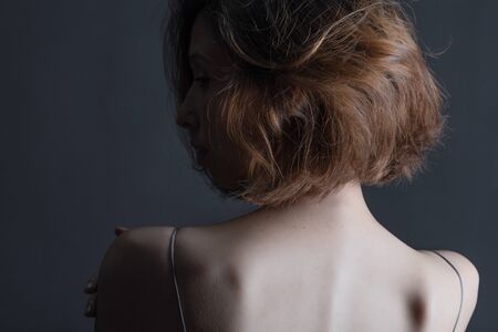 Portrait of a beautiful, sensual girl on a gray background in a gray dress. Youth and skin care...