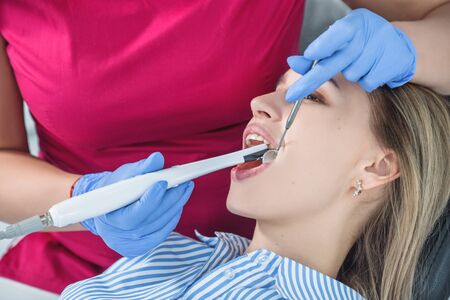 A dentist examines a patient, close-up of a patient with an open mouth next to which dental objects.