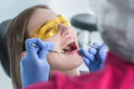 A dentist examines a patient, close-up of a patient with an open mouth next to which dental objects.の写真素材