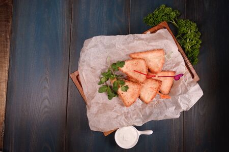 Appetizing fried cheese with sauce on a wooden tray. Studio photography of food in the cooking...