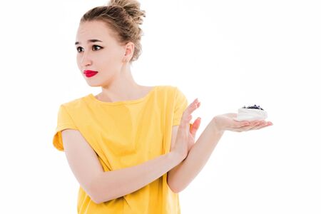emotional portrait of a girl who refuses a cake on an isolated white background. The concept of a healthy diet and refusal of sweet and junk foodの写真素材