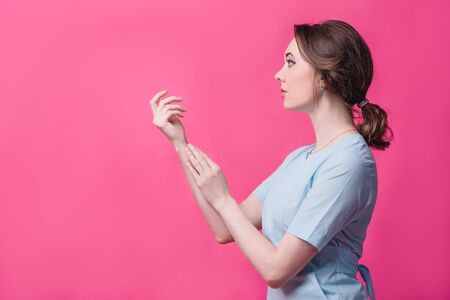 Beautiful girl gently touches her hands on a pink background in the studio. The concept of beauty, care, cosmetology and massageの写真素材