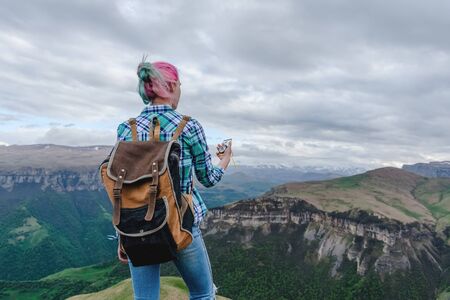 A beautiful girl stands high in the beautiful mountains with a compass in her hands. The concept of navigating the search for your own path and orientation to the cardinal points.の写真素材