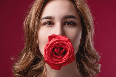 Portrait of a beautiful girl with bare shoulders and a rose. The concept of youth, beauty and a...